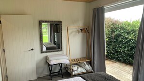A bedroom with a bed, a bedside table, a mirror, and a wooden wardrobe.