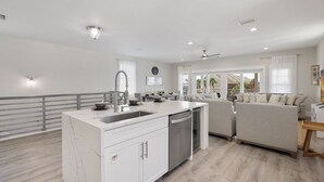 Eine moderne Küche mit einer zentralen Kochinsel, integriertem Geschirrspüler und einem Essbereich mit Sofa und Tisch.