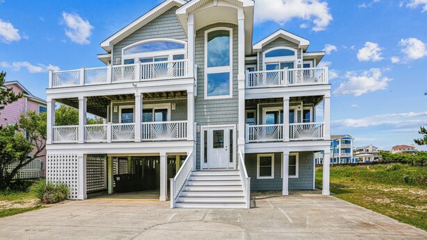 A two-story house with a central entrance, multiple balconies, and a large window on the second floor. - 220ft from beach access! Private pool, hot tub. Summer deals! (Corolla)