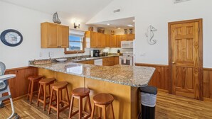 A kitchen with wooden cabinets, a granite countertop, a microwave, and a seahorse decoration. - 220ft from beach access! Private pool, hot tub. Summer deals! (Corolla)