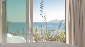 A bedroom with a large window overlooking a beach. - Seascapes Waterfront 2 (Paraparaumu)