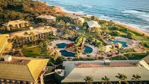 Resort com várias piscinas, palmeiras e vista para a praia.
