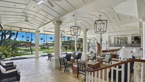 Um espaço amplo e interno, com teto alto, janelas grandes e vista para um jardim bem cuidado.