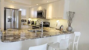 Una cocina moderna con armarios blancos, electrodomésticos de acero inoxidable y encimera de granito.