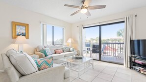 Una sala de estar con un sofá, sillones, una mesa de centro, televisor y un balcón con vistas.