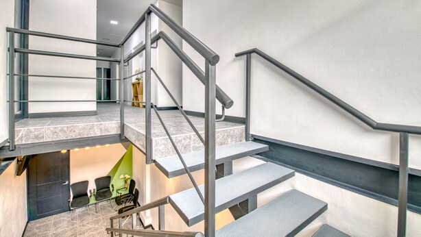 A modern staircase with metal railings and a view of a lounge area with chairs and a table. - Private Apartment in the Heart of San Jose! (San Jose)