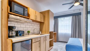 A compact kitchen with a microwave, stove, and sink, adjacent to a bed with a blue cover. - Private Apartment in the Heart of San Jose! (San Jose)
