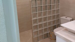 Un baño con suelo de baldosas, inodoro, lavabo y ventana.