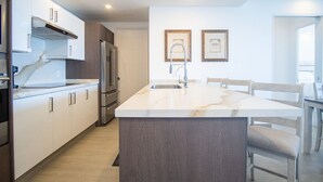 Una cocina moderna con una isla central, electrodomésticos de acero inoxidable y un comedor con sillas de madera.
