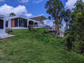 Una casa moderna con un patio delantero amplio, un balcón y una escalera que conduce al piso superior.