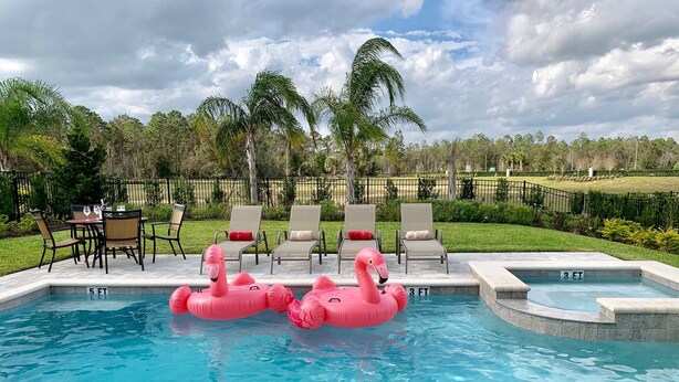 Ein Swimmingpool mit zwei rosa Flamingo-Schwimmpfauen, Liegestühlen und einem Tisch mit Stühlen.