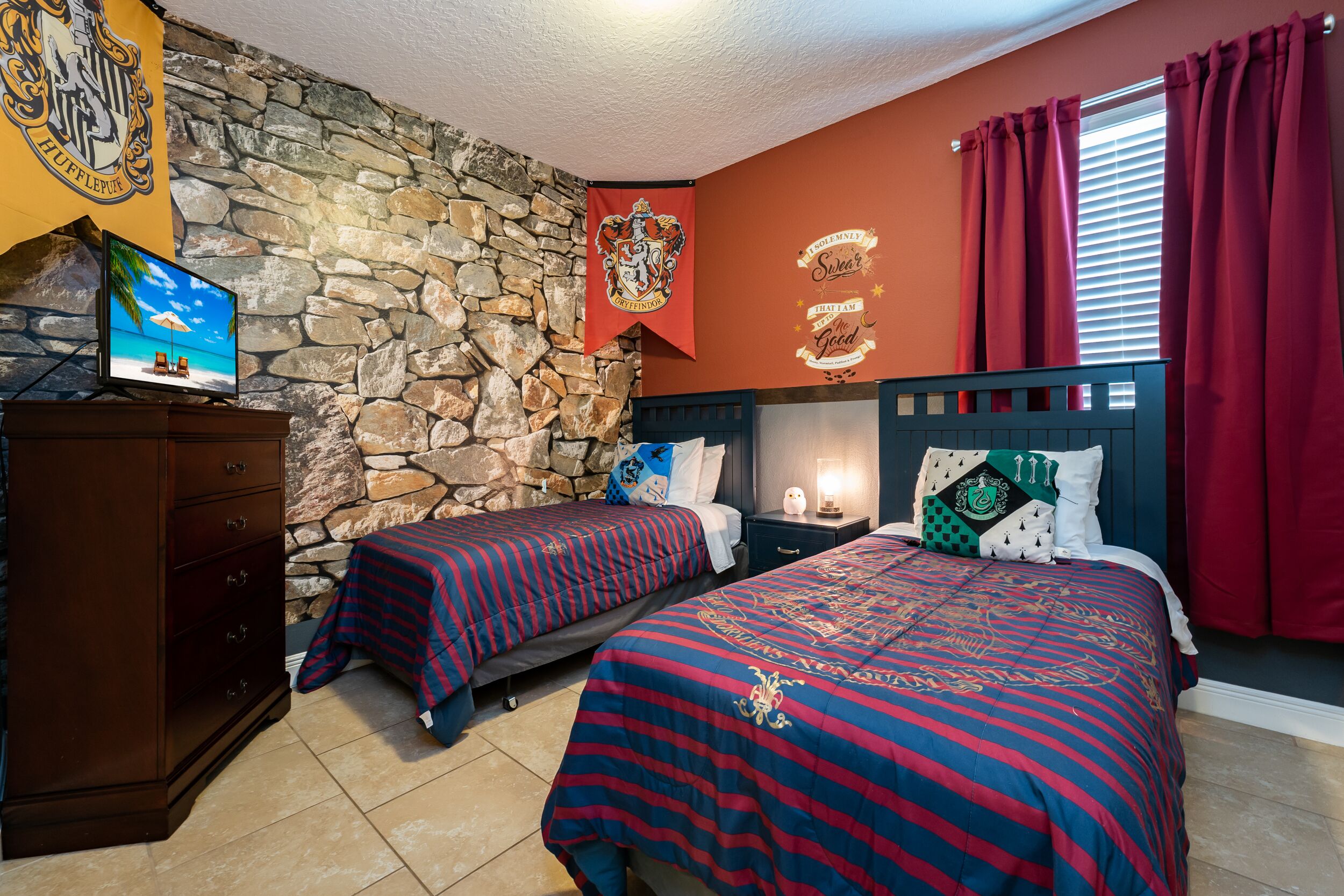 A bedroom with two beds, a stone wall, a television, and a banner.