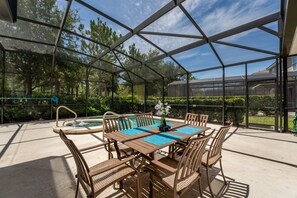 Un espace extérieur abrité comprenant une piscine, une table avec des chaises et une vue sur la verdure environnante.