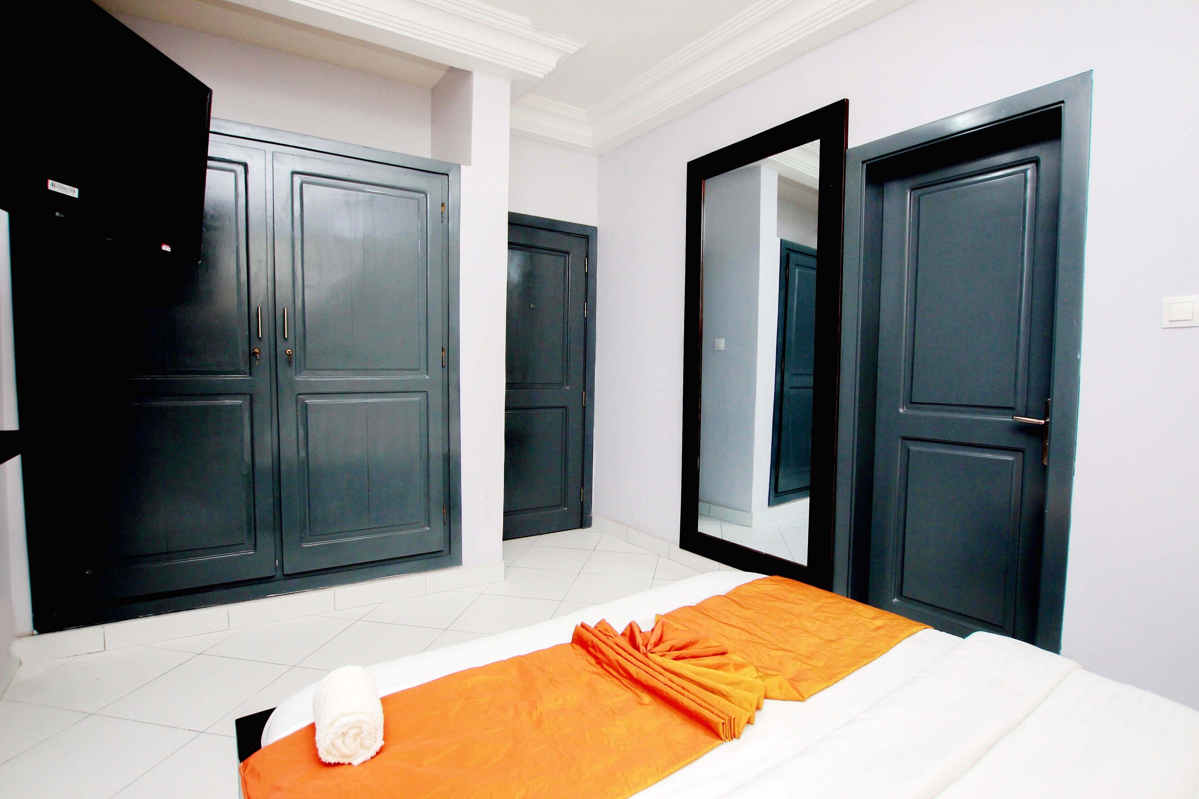 Un dormitorio con cama, un espejo grande y dos puertas.