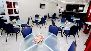 A hotel dining area with round tables, blue chairs, and glass tops. - Hotel Galilée (Cotonou)