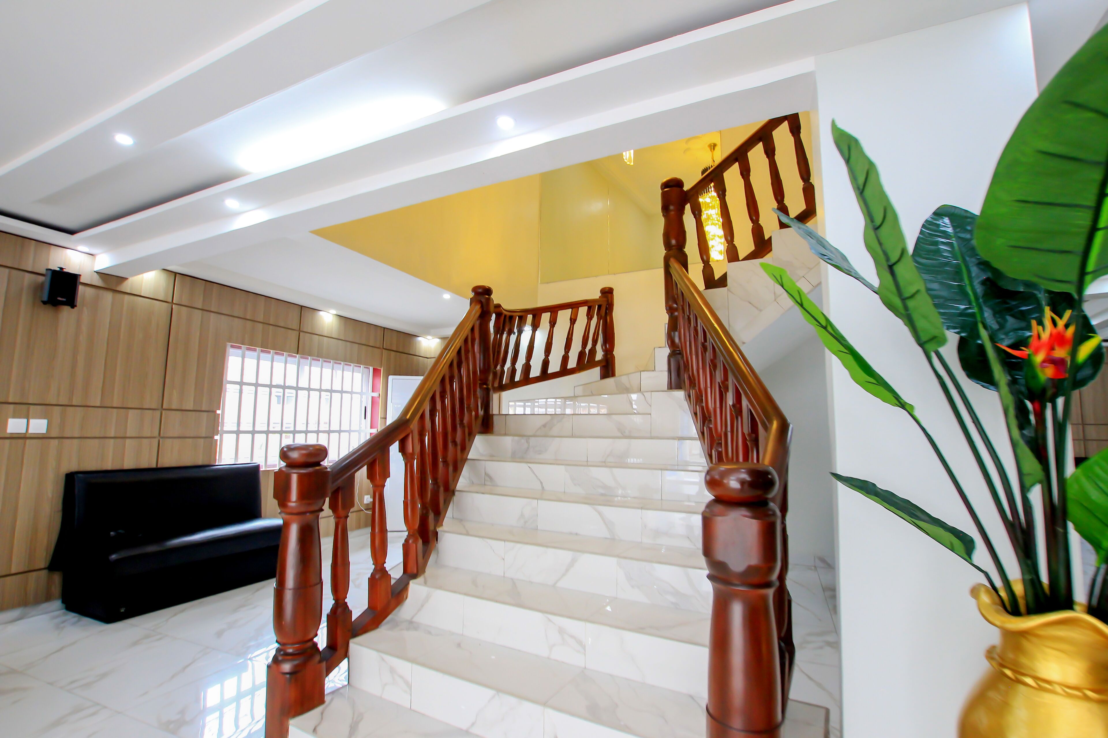 A staircase with wooden railings, marble steps, and a potted plant with a flower.