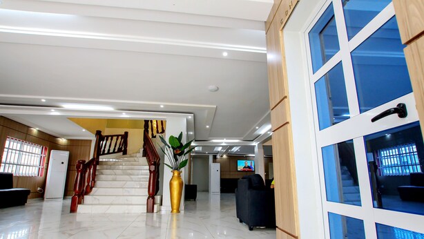 A spacious lobby with a marble floor, a staircase, a reception desk, and a television screen. - Hotel Galilée (Cotonou)