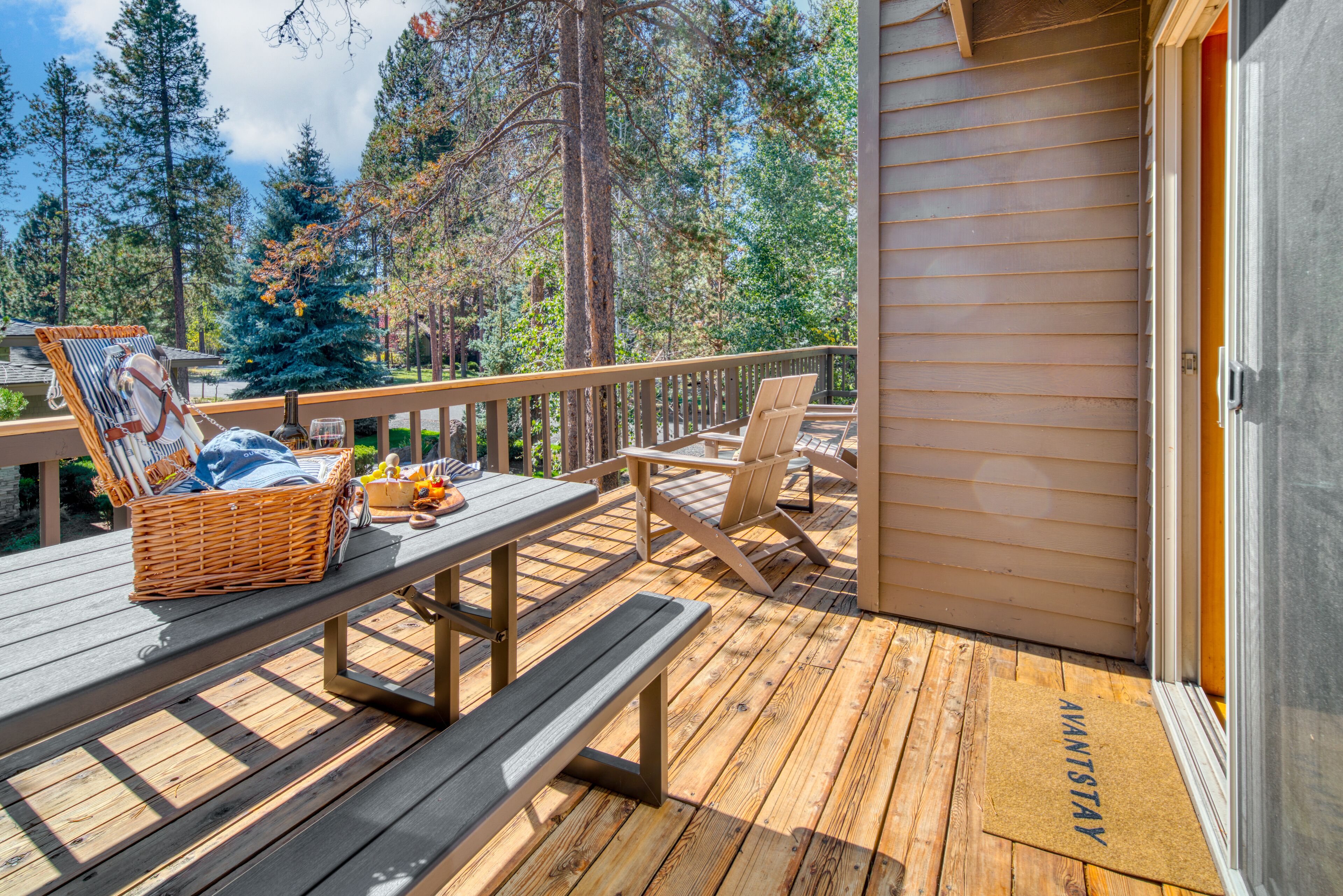 Terraza de madera con mesas de picnic, sillas y una cesta de mimbre.