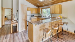 Una cucina moderna con mobili in legno, un piano di lavoro in granito e sgabelli da bar.