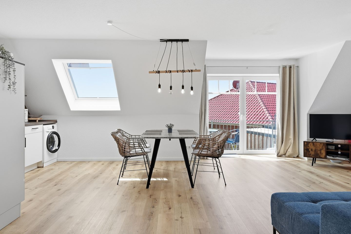 A modern apartment with a dining area, a TV, and a balcony with a red roof.