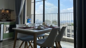 Uma sala de jantar com uma mesa posta para quatro pessoas, uma cozinha com eletrodomésticos modernos e uma grande janela com vista para a cidade.