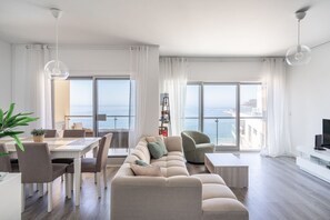 Uma sala de estar moderna com sofá, mesa de jantar, cadeiras e televisão.
