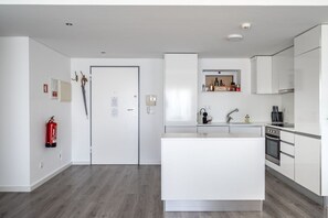 Eine moderne Küche mit weißen Schränken, einer Kochinsel und einem eingebauten Backofen.