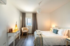 Une chambre d’hôtel avec un lit, un bureau, une chaise et une fenêtre avec des rideaux.
