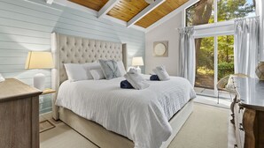 Een slaapkamer met een groot bed, een houten plafond en uitzicht op de omgeving.
