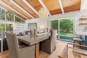 A modern kitchen with a large dining table, chairs, and a view of the outdoors.