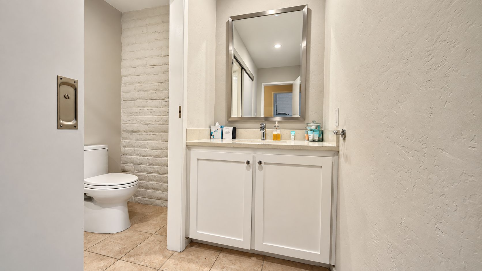 A bathroom with a toilet, a sink with a mirror, and a cabinet.