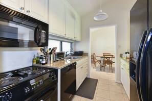 Une cuisine compacte équipée d’une cuisinière, d’un four à micro-ondes, d’un évier et d’un coin repas avec une table et des chaises.