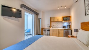 A hotel room with a bed, a TV, a kitchenette, and a small dining area. - Stylish Downtown Studio Apartment with Patio & A/C! (San jose)