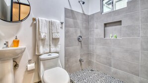 A modern bathroom with a toilet, sink, and shower. - Stylish Downtown Studio Apartment with Patio & A/C! (San jose)