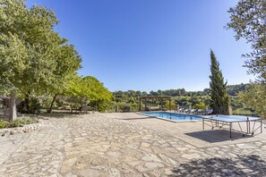 Un espace extérieur dallé de pierres, avec une piscine, des chaises longues et une pergola.