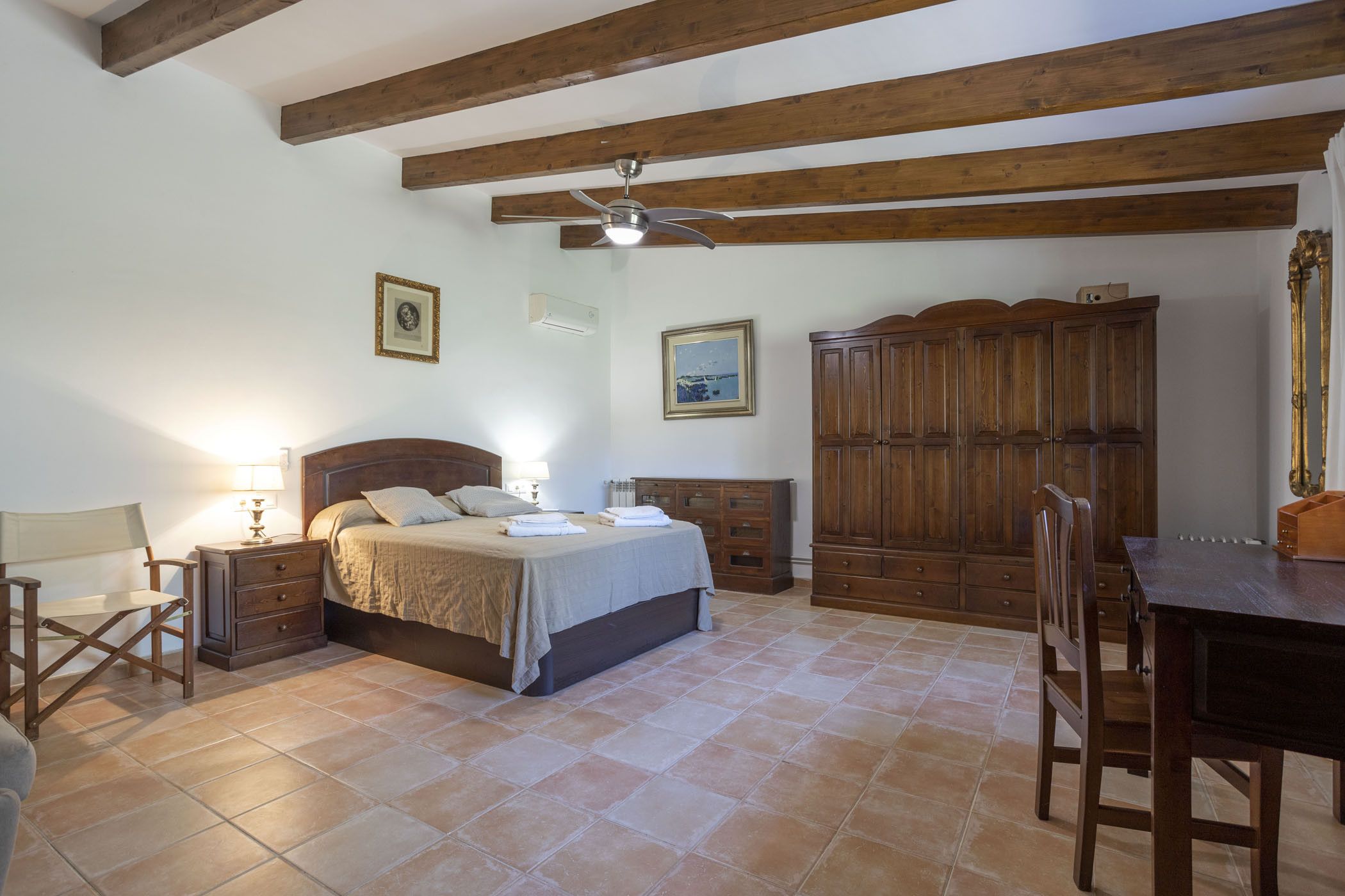 Un dormitorio con cama, armario de madera y escritorio con silla.