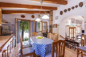 A dining area with a checkered tablecloth, wooden chairs, and a view of the outdoors. - Fantastic Villa for 12 people with pool and barbecue. (Caimari)