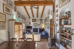 A cozy living room with a wooden ceiling, a fireplace, and a bookshelf filled with books and decorative items. - Fantastic Villa for 12 people with pool and barbecue. (Caimari)