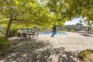 Une terrasse en pierre avec une piscine, du mobilier d’extérieur et une vue sur la campagne.