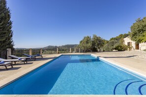 A rectangular swimming pool with clear blue water, surrounded by lounge chairs and a stone wall. - Fantastic Villa for 12 people with pool and barbecue. (Caimari)