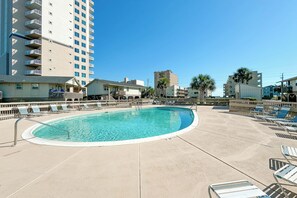 A swimming pool with lounge chairs and a high-rise building in the background. - Gulf Village 109 | Direct Beach Access | Outdoor Pool | Ocean View | My Beach Getaways (Gulf Shores)