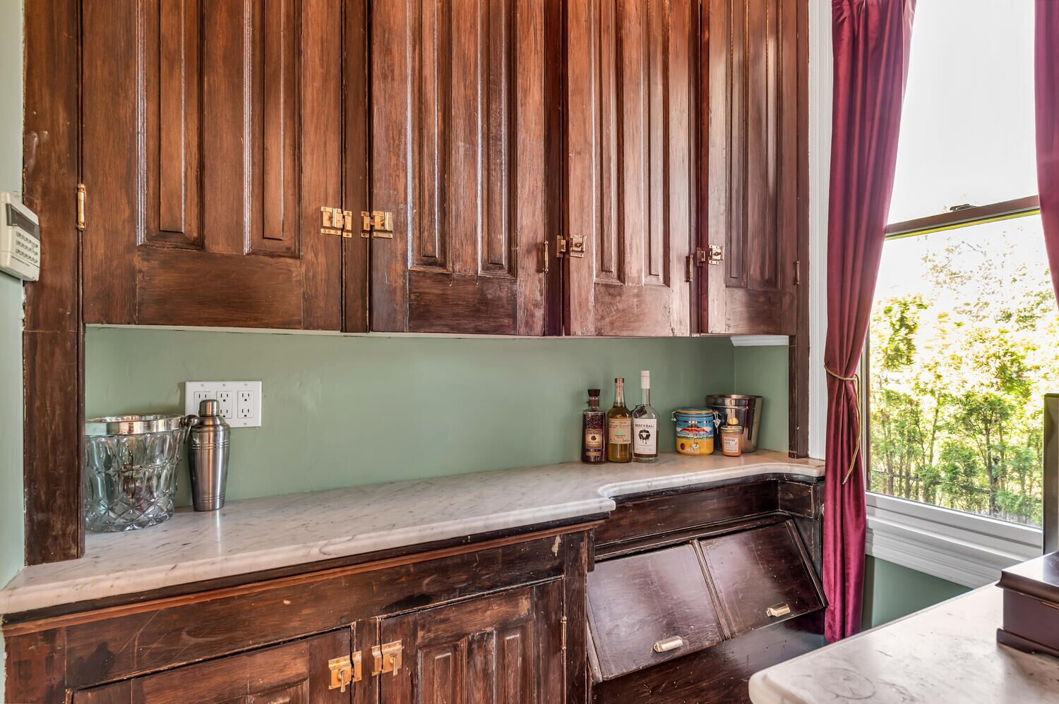 A kitchen with wooden cabinets, a marble countertop, and various kitchen items.