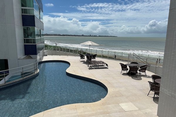 Una piscina al aire libre, sombrillas, sillones reclinables de piscina