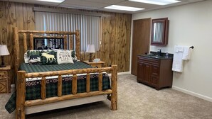 Une chambre à coucher avec un lit à baldaquin en bois, une armoire en bois, un miroir et une fenêtre avec des stores.