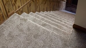 Un intérieur en bois avec un escalier recouvert de moquette et une main courante.