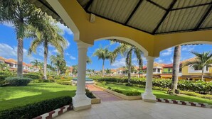 Un espacio exterior cubierto con suelo de baldosas, palmeras y un jardín bien cuidado.