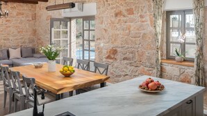 A dining area with a stone wall, a wooden table, and a marble countertop.