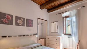 A bedroom with a bed, a dresser, a mirror, and a window with curtains. - Nice apartment for 6 guests with terrace and pets allowed (Dolcedo)