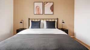 A modern bedroom with a large bed, two bedside tables, and abstract artwork on the wall. - Bright Horgen 2.5 Room w/ Storage, 3 min to Market, by Blueground (Zurich)