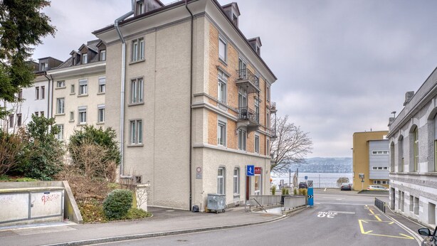 A multi-story residential building with a parking area in front. - Bright Horgen 2.5 Room w/ Storage, 3 min to Market, by Blueground (Zurich)